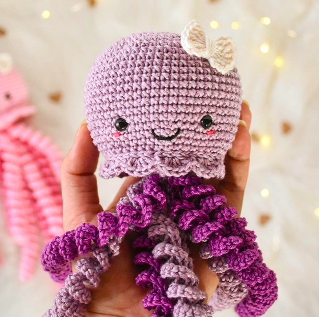 Step-by-step crochet octopus tutorial featuring a lavender amigurumi octopus with eight curly tentacles, white underside, embroidered sleepy eyes, and pink cheeks.